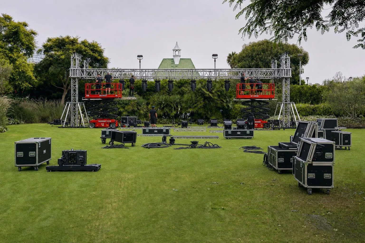 Lighting technicians on a genie lift pre-rigging aluminum truss and moving heads with road cases and DMX cable on the floor