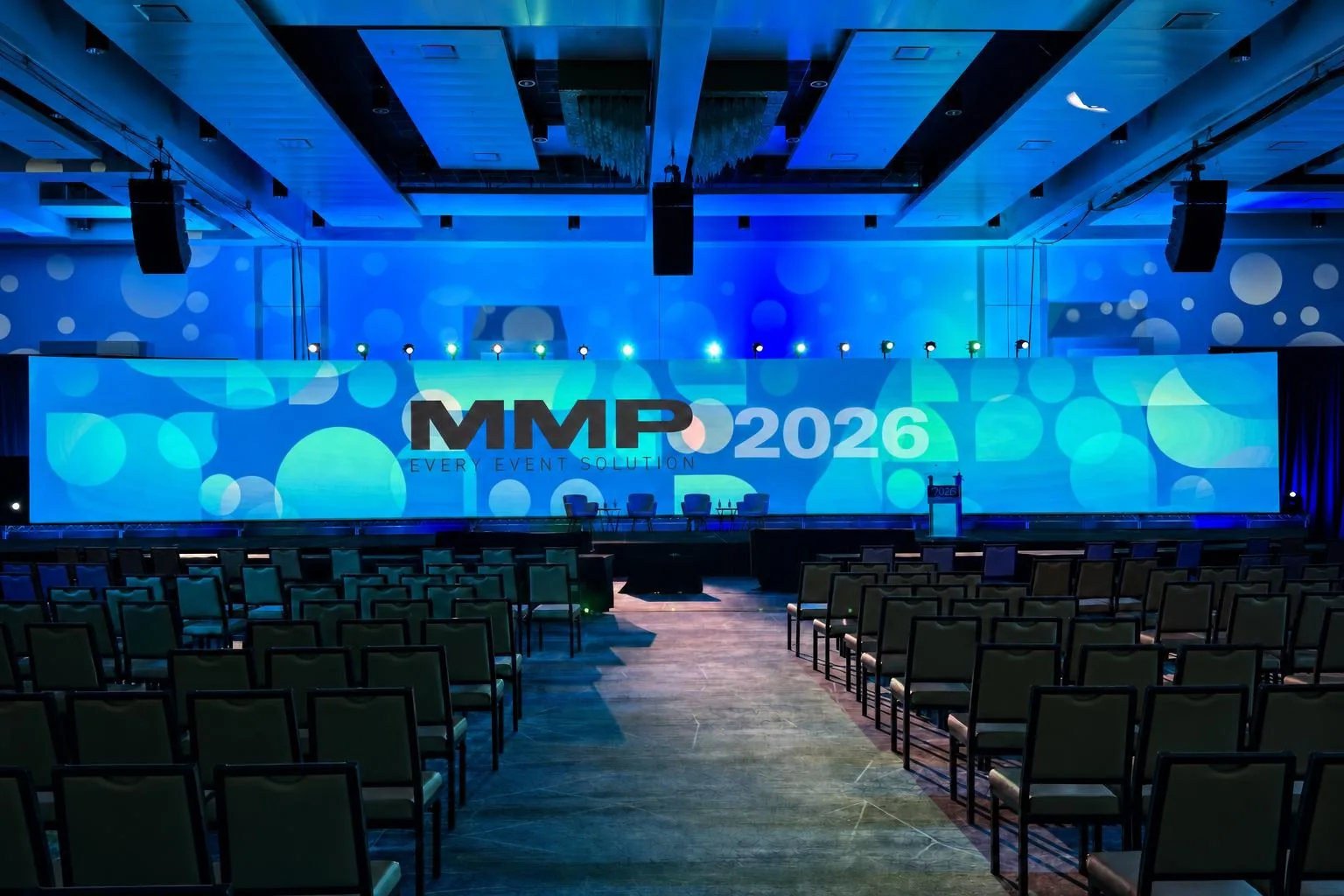 Large corporate general session with LED wall and packed ballroom under teal stage lighting